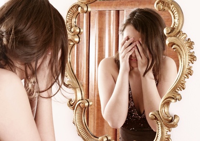 woman being hard on herself while reflecting in mirror